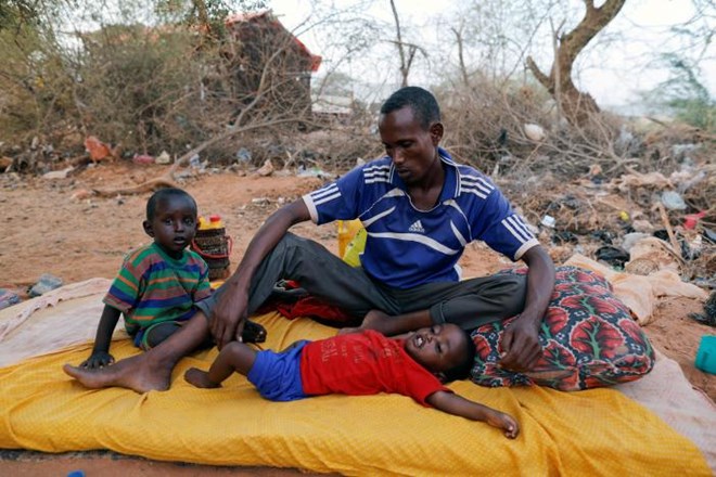 FILE PHOTO: A Somali internally displaced man from drought-hit area sits with his children as he waits for help in Dollow, Somalia April 3, 2017. REUTERS/Zohra Bensemra/File photo